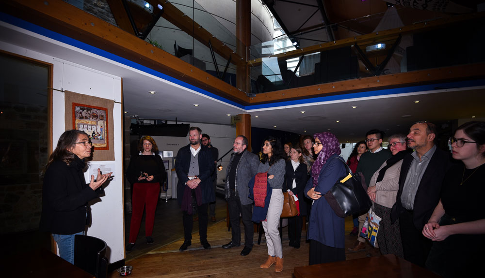 Attendees absorbing the arpilleras and listening to the insights of curator Roberta Bacic during the guided tour at the 