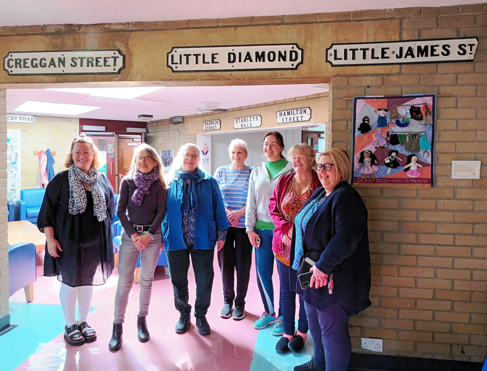 Women from the Peace Barriers Programme, Bogside and Brandywell Initiative with Conflict Textile facilitators and Peace Barriers Programme staff at the launch of their collective textile 'Derry Dolls - Past to Present'. (Photo: Conflict Textiles Archive)