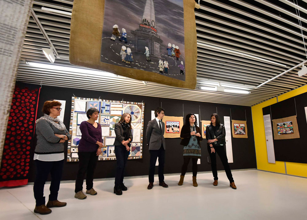 Members of the organising team, encircled by textile pieces, at the launch of the exhibition: 