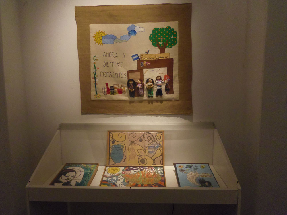 The arpillera “Irene, Marta, Hilda, Patricia: Ahora y Siempre Presentes / Irene, Marta, Hilda, Patricia: Now and Always Present” on display with commemoration tiles from Escuela de Cerámica. (Photo: Ana Zlatkes)